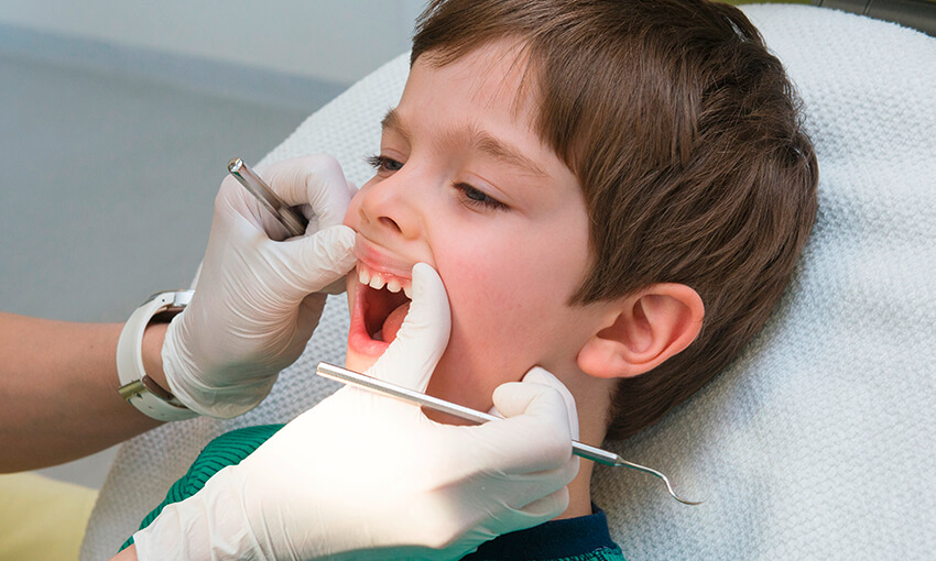 Zahnarzt beim Betrachten des Lippenbändchens eines Jungen